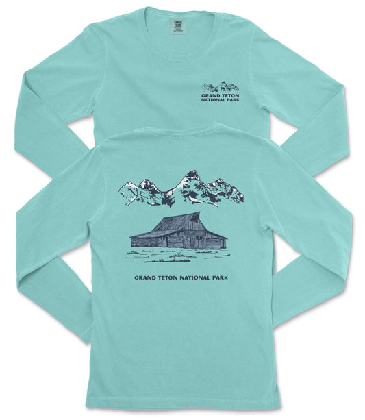 A turquoise long-sleeved t-shirt with a graphic design depicting a cabin and mountains, along with text that reads "Grand Teton National Park".