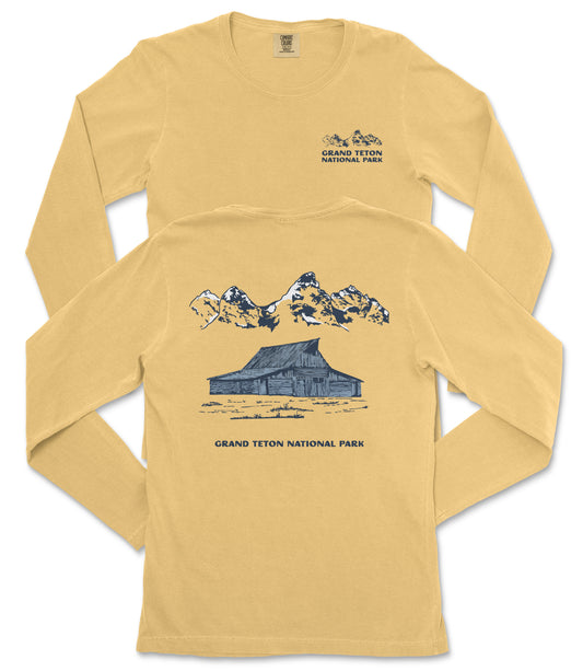 A yellow long-sleeved t-shirt with a graphic design depicting a cabin and mountains, along with text that reads "Grand Teton National Park".