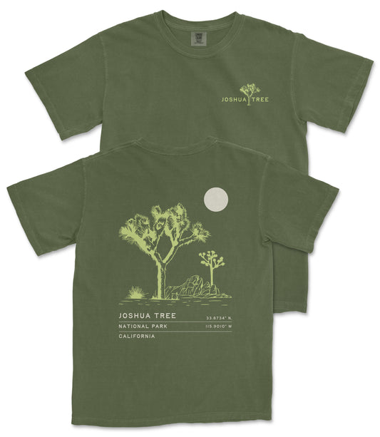 A green t-shirt with a graphic design depicting a desert landscape, including a tree and a moon, along with text that reads " Joshua Tree National Park California".