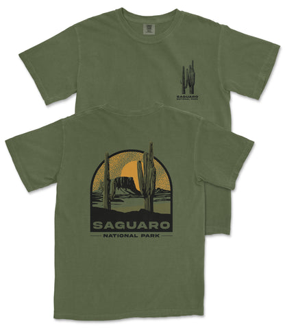 A green t-shirt with a graphic design depicting a desert landscape with cacti and mountains, along with the text "Saguaro National Park".