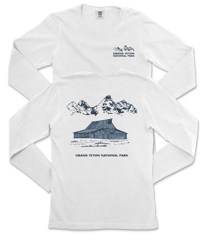 A white long-sleeved t-shirt with a graphic design depicting a cabin and mountains, along with text that reads "Grand Teton National Park".