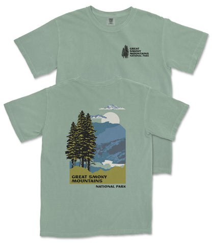 A green t-shirt with a graphic design depicting a mountain landscape with pine trees, a full moon, and clouds. The text on the t-shirt reads "GREAT SMOKY MOUNTAINS NATIONAL PARK".
