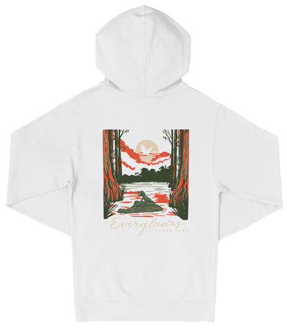 A white hooded sweatshirt with a graphic design depicting a sunset over a body of water, surrounded by trees and foliage.