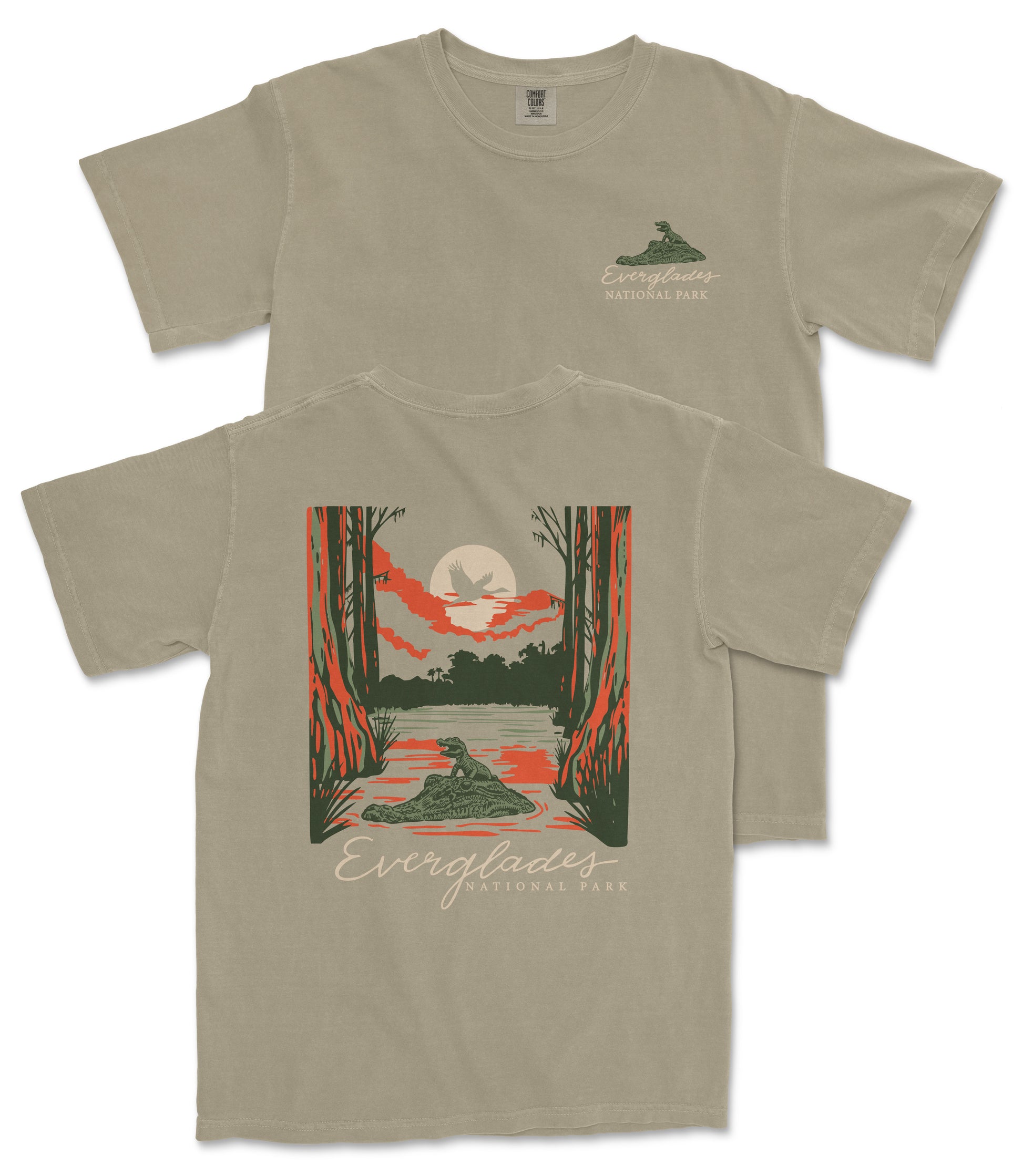 a t-shirt with a graphic design depicting a serene natural scene, including a lake, trees, and a bird.