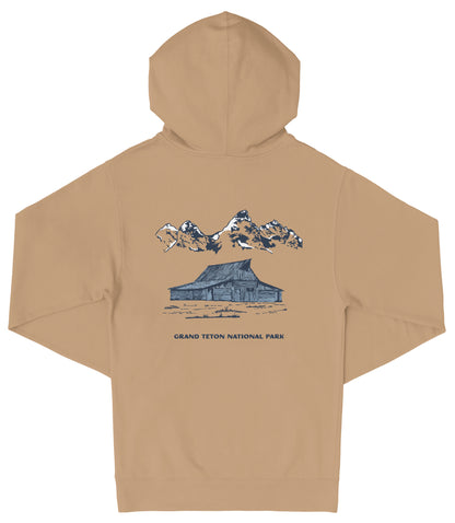 A tan hooded sweatshirt with a graphic design depicting a cabin and mountains in the background, along with the text "Grand Teton National Park".