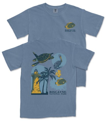 A blue t-shirt with a graphic design depicting various elements associated with Biscayne National Park, including a lighthouse, palm trees, and fish.