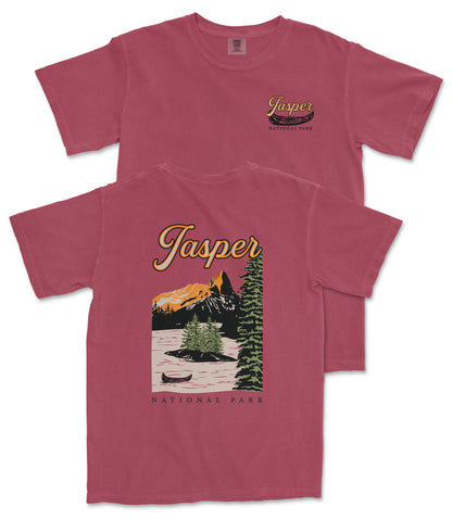 A red t-shirt with a graphic design depicting a scenic landscape with mountains, a lake, and a canoe, along with the text "Jasper National Park".