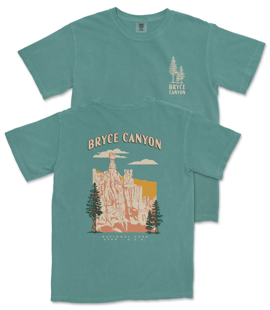 A green t-shirt with a graphic design depicting Bryce Canyon National Park, featuring a mountain landscape with trees and a cloud in the background.