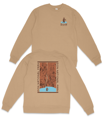 a tan sweatshirt with a graphic design on the back, depicting a person standing in front of a canyon or mountain range.