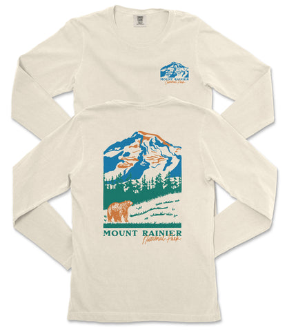 a cream-colored long-sleeved t-shirt with a graphic design depicting a mountain landscape, including a bear and trees. The text "MOUNT RAINIER" is prominently displayed, indicating the location or theme of the design.