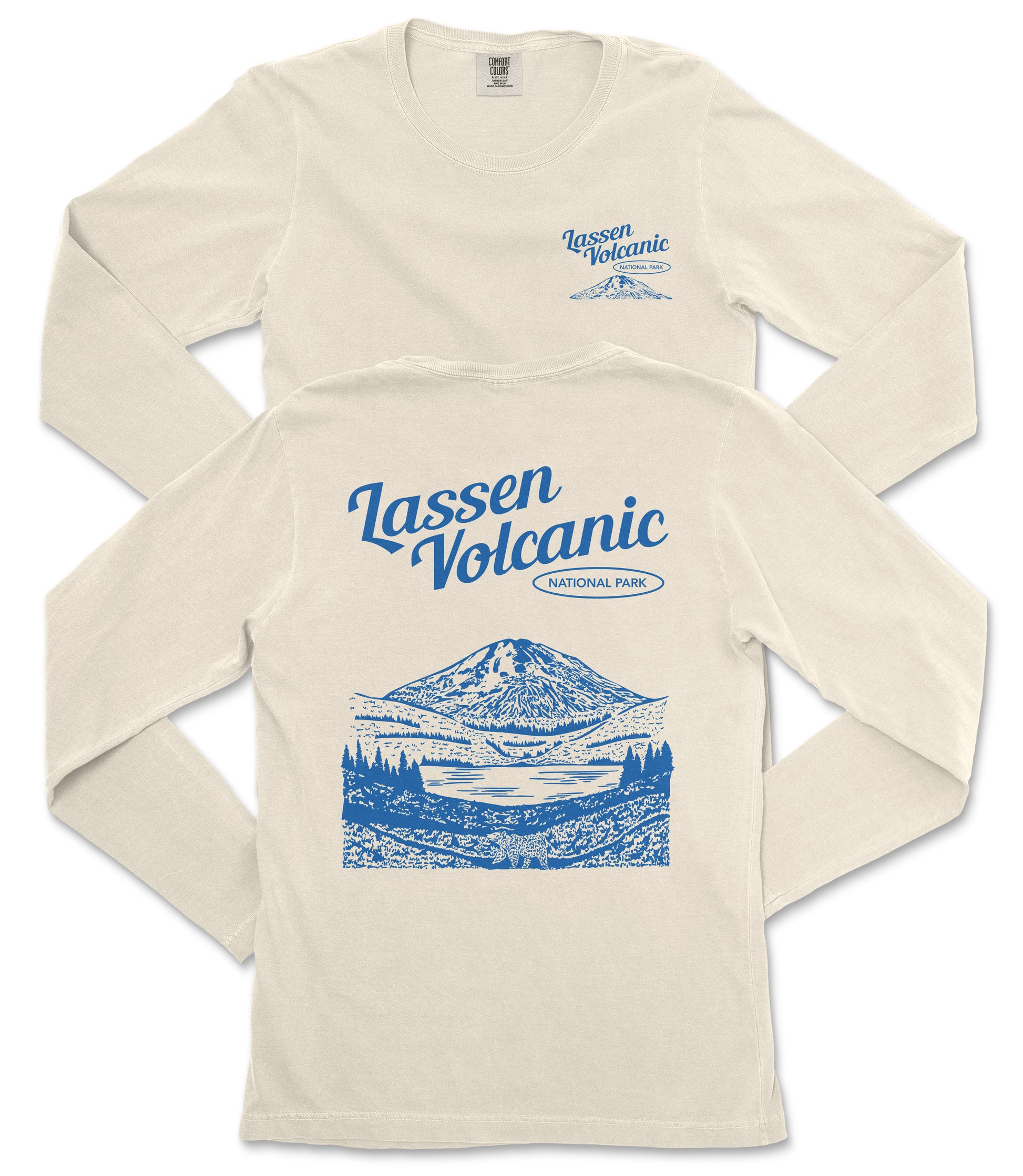 a cream-colored long-sleeved t-shirt with a graphic design depicting a mountain landscape and a lake. The design includes the text "Lassen Volcanic National Park" printed on the back of the shirt.