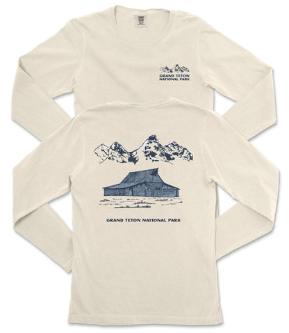 a cream-colored long-sleeved t-shirt with a graphic design depicting a cabin and mountains, along with the text "Grand Teton National Park" printed on the back.