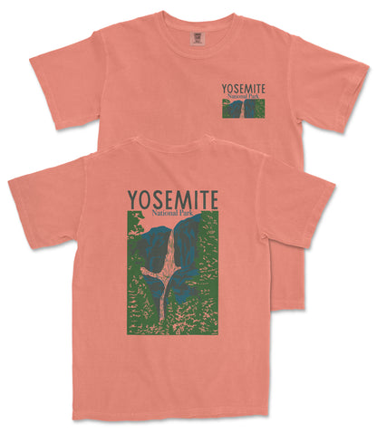 A peach-colored t-shirt with a graphic design depicting a mountain range and the text "Yosemite National Park" printed on it.