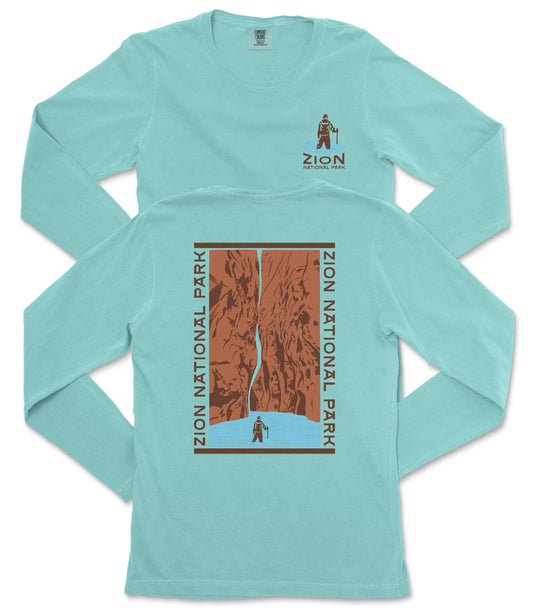 A turquoise long-sleeve t-shirt with a graphic design depicting a person standing in front of a canyon or waterfall.