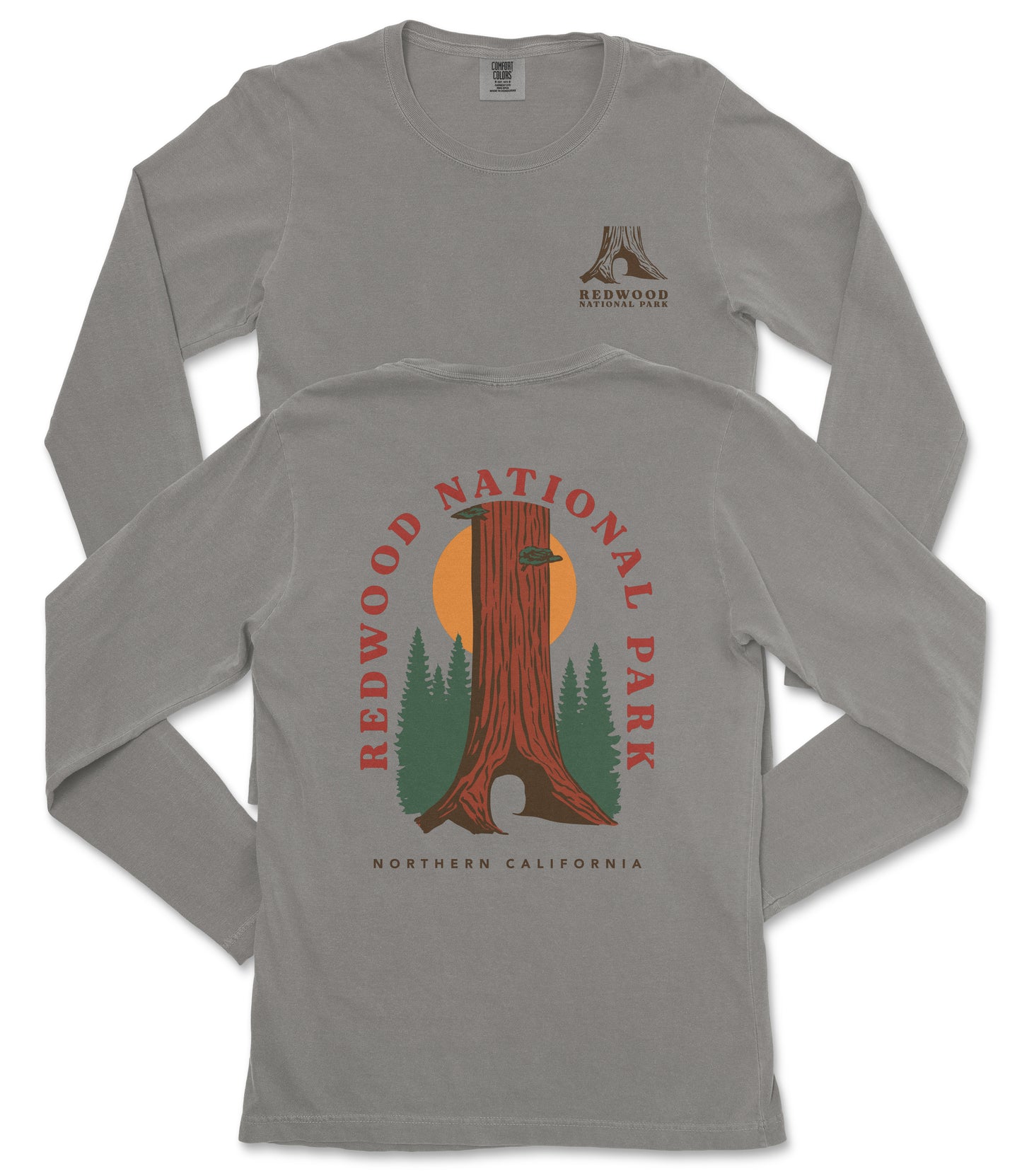 a gray long-sleeved t-shirt with a graphic design depicting a tall tree with a sun-like symbol in the center, surrounded by green trees and mountains. The design is related to Redwood National Park in Northern California.