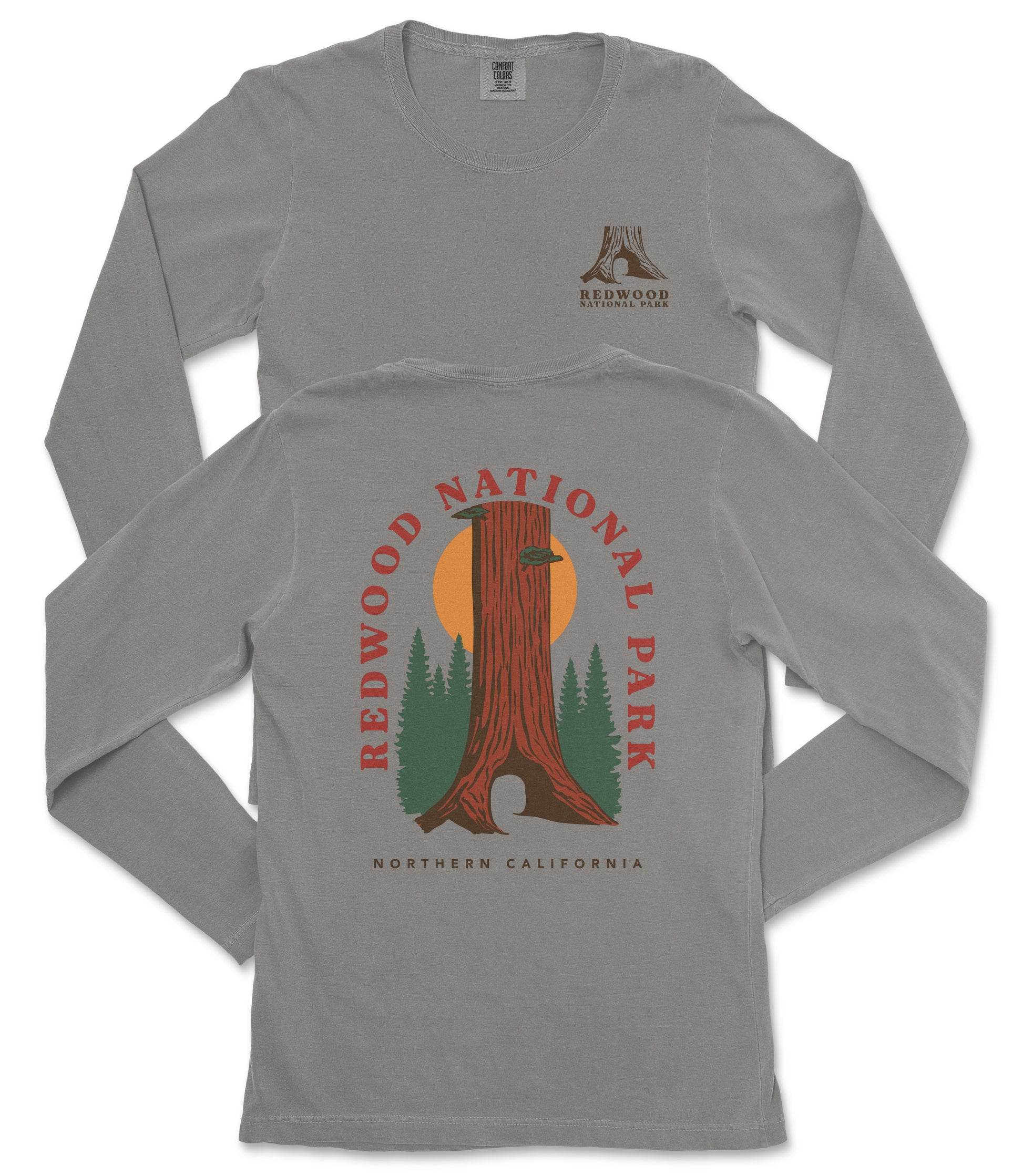 a gray long-sleeved t-shirt with a graphic design depicting a tall tree with a sun-like symbol in the center, surrounded by green trees and mountains. The design is related to Redwood National Park in Northern California.