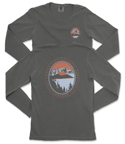 a gray long-sleeve t-shirt with a graphic design on the back. The design depicts a mountain landscape with a lake and trees, and includes the text "Cater Lake National Park, Oregon" around the edge of the circle.