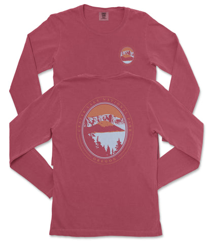 a red long-sleeved t-shirt with a graphic design on the back. The design features a circular emblem with a mountain landscape and a sunset.