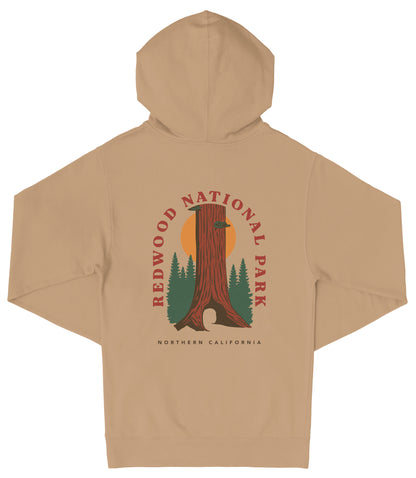 A beige hooded sweatshirt with a graphic design depicting a tall tree with a sun-like symbol in the center, surrounded by pine trees.