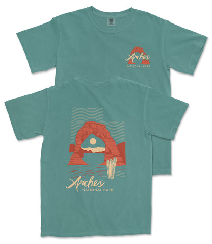 A turquoise t-shirt with a graphic design depicting the Arches National Park, featuring a red arch and a desert landscape.